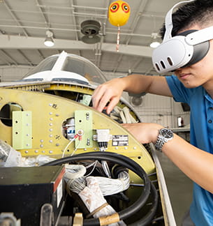 Embry-Riddle student in virtual reality glasses works on a plane