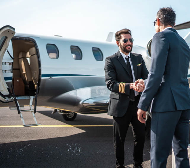 Two men shaking hands outside of an airplane.
