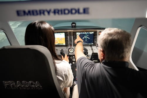 A student uses the Frasca flight simulator with an instructor on the Prescott campus.