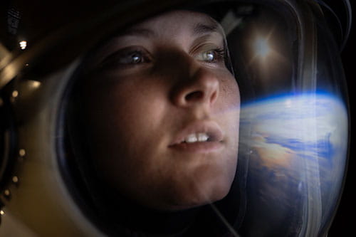 Closeup of astronaut with a reflection of Earth in their helmet