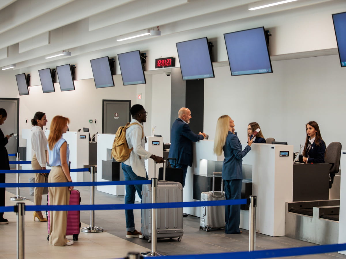 Customers checking in bags at an airport terminal.