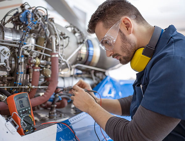 Mechanic using multimeter while working on a helicopter