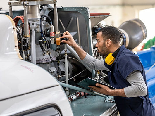 Mechanic with clipboard checking on helicopter in a hangar