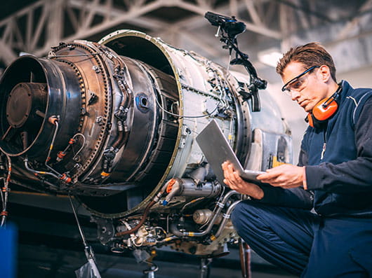 Aircraft engineer in hangar holding a laptop