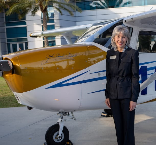 A woman stands in front of an airplane