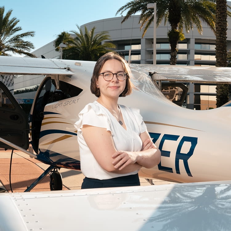 A young woman standing next to an Embry-Riddle aircraft