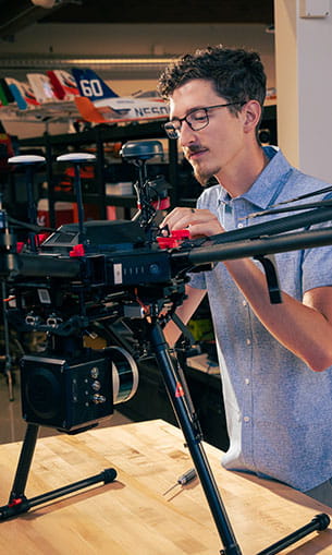 A student works with an uncrewed system in a lab setting.