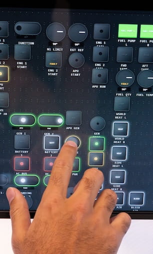 Hand interacting with aircraft avionics touchscreen displaying flight control and system interface.