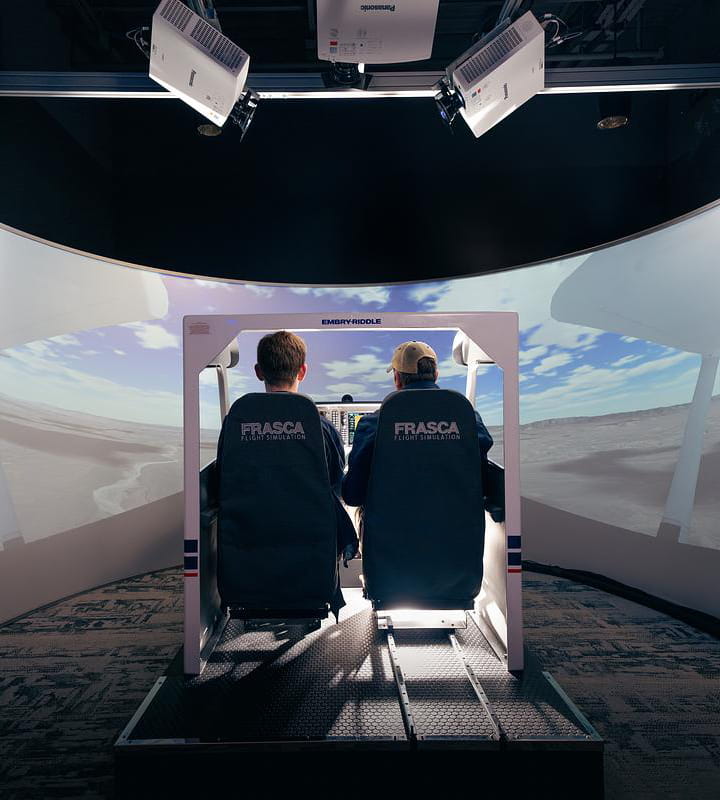 Two people using a flight simulator.
