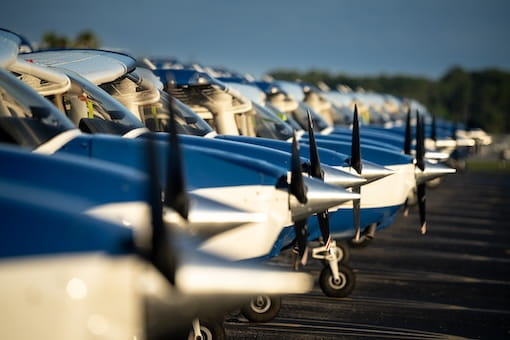 A row of small aircrafts sitting on a runway.