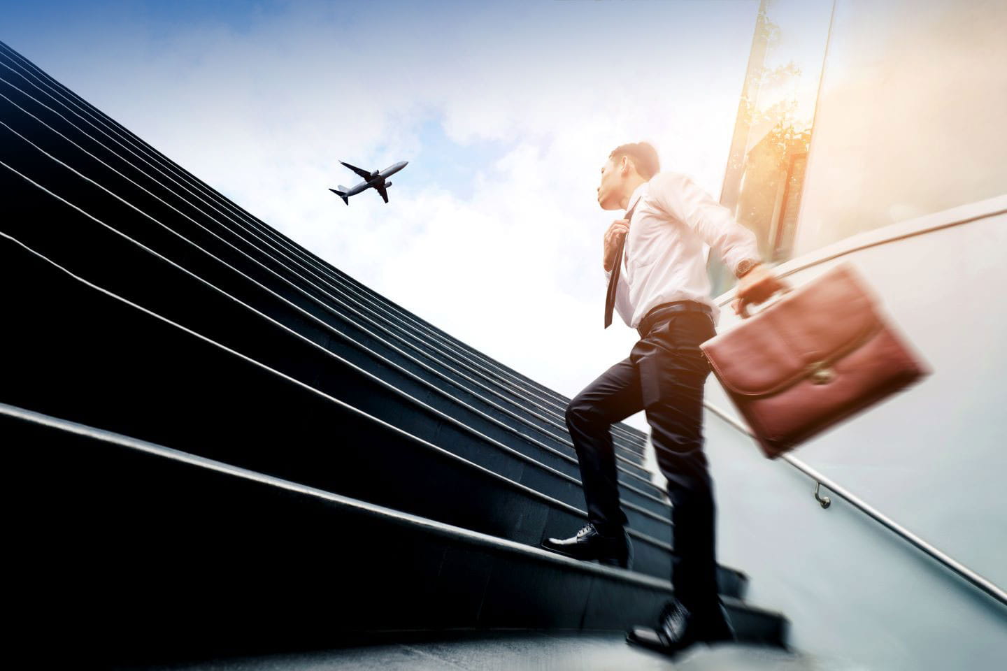 A person wearing business attire, holding a bag, walking up steps,