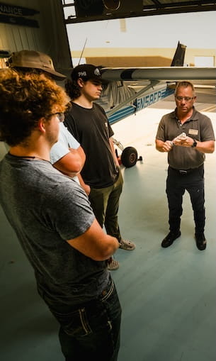 A group of people standing inside an aircraft hangar.
