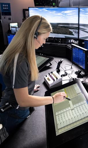 An individual with headphones on, working inside an air traffic control room.