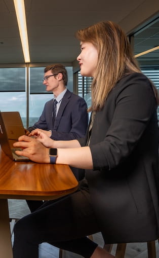 Two students in business suits at a conference table.