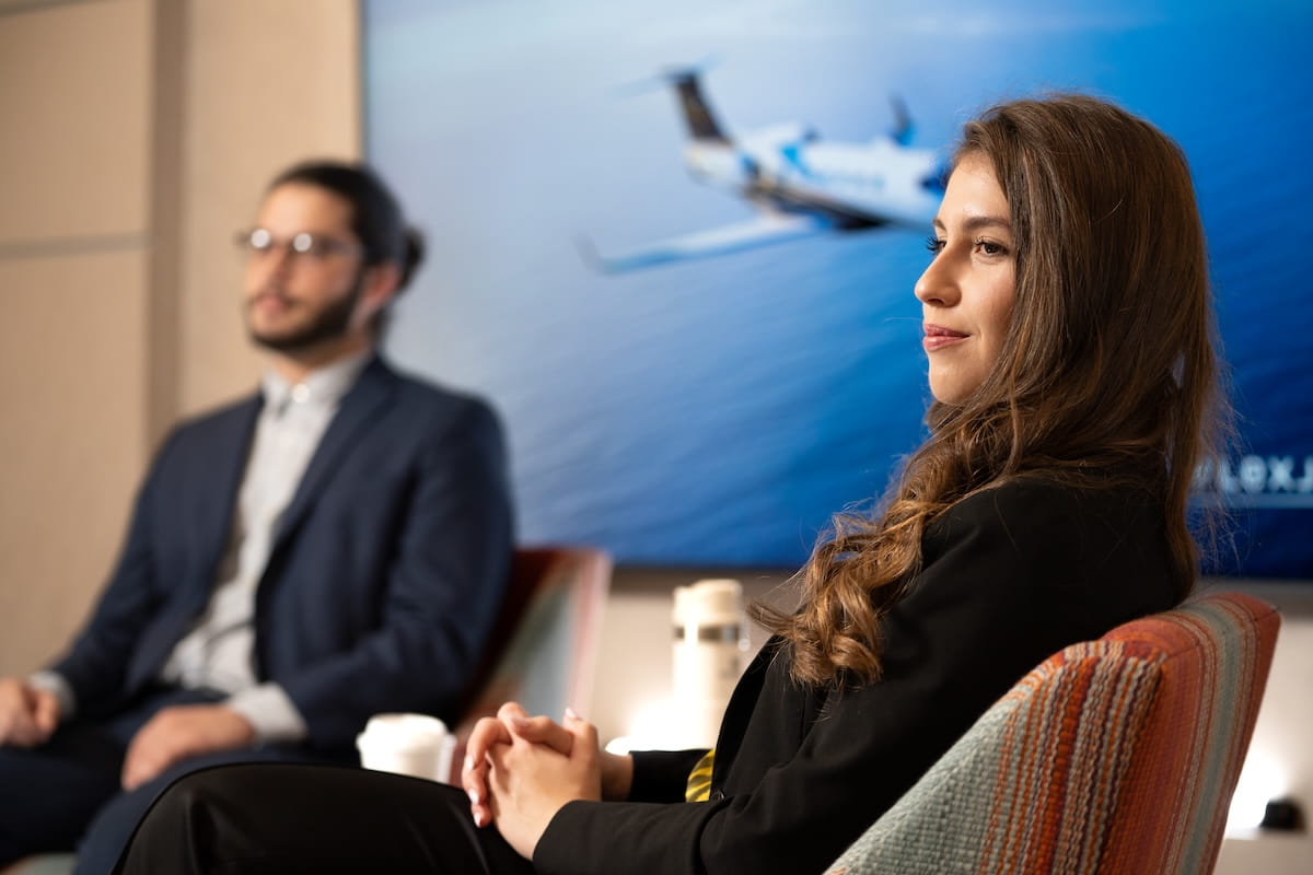 Students in business attire seated during presentation with aircraft image displayed on screen behind.