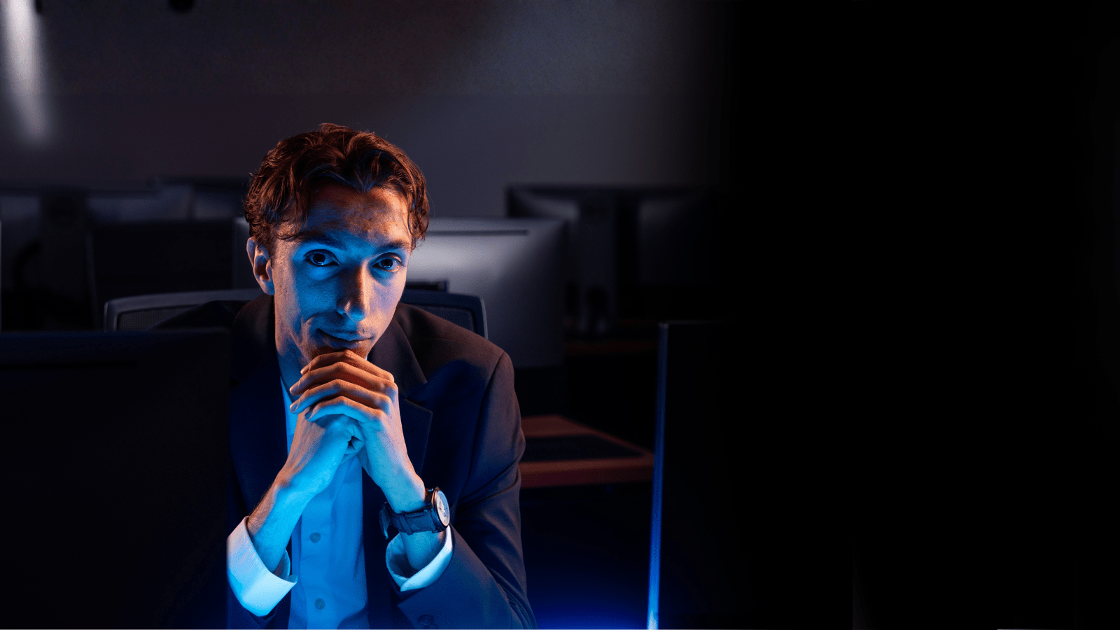 A student wearing business attire, sitting at a desk.