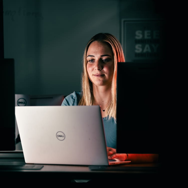 A student sitting at a desk, working on a laptop.