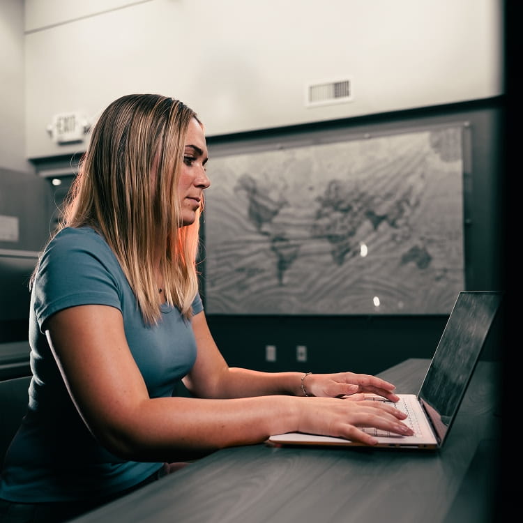 A student sitting at a desk, working on a laptop.