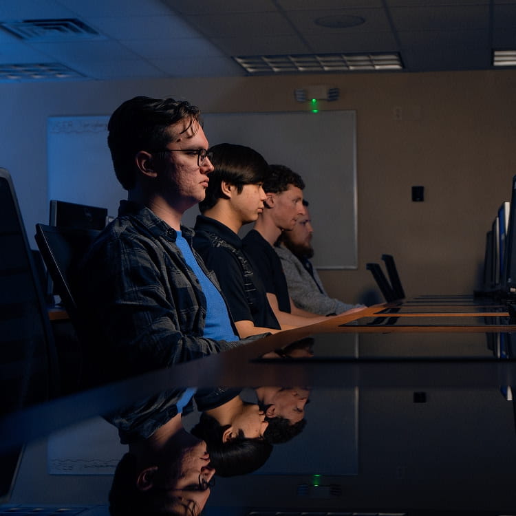 Three students sitting together, working on computers.