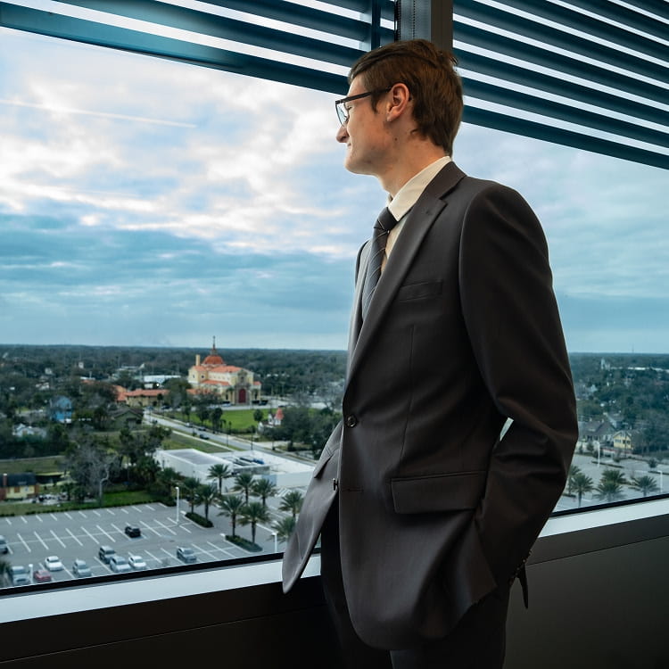 A person in a business suit looking out a window.