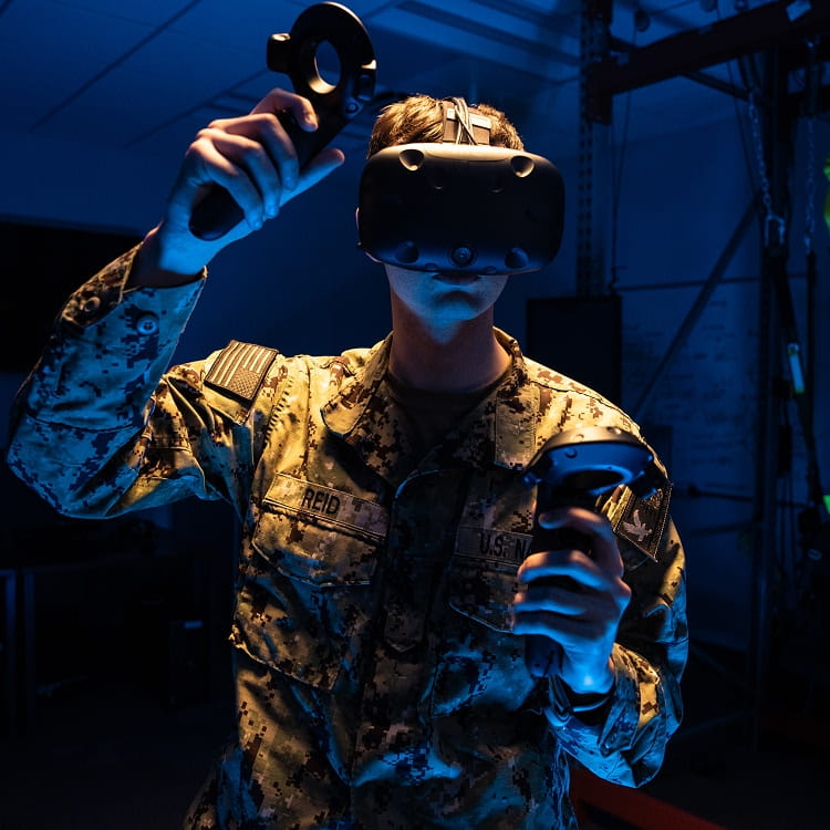 A person wearing a military uniform while operating a virtual reality simulator.