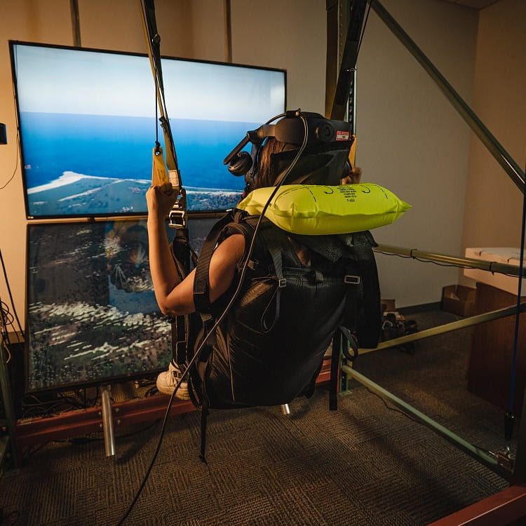A person seated in a parachute simulator.