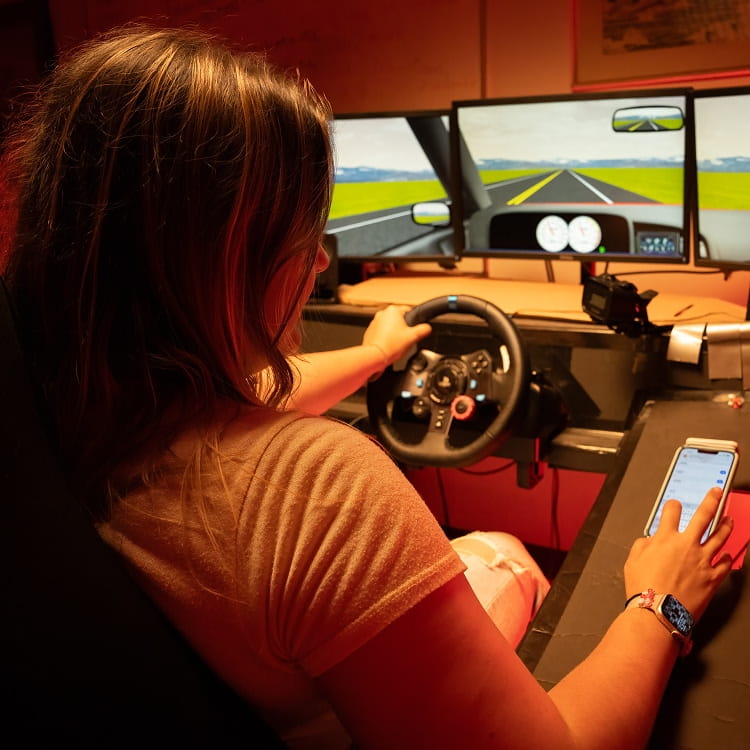 A person seated and operating a simulator.