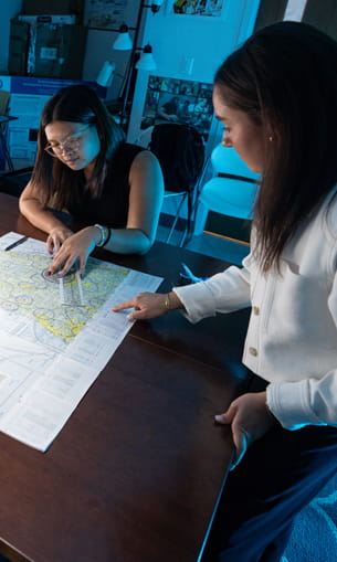 Two people collaborate at a desk while reviewing a map.
