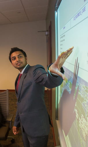 A person in a suit points toward a projected display.