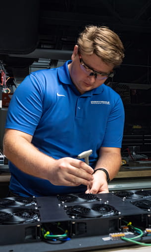 A person wearing safety goggles, working on equipment.