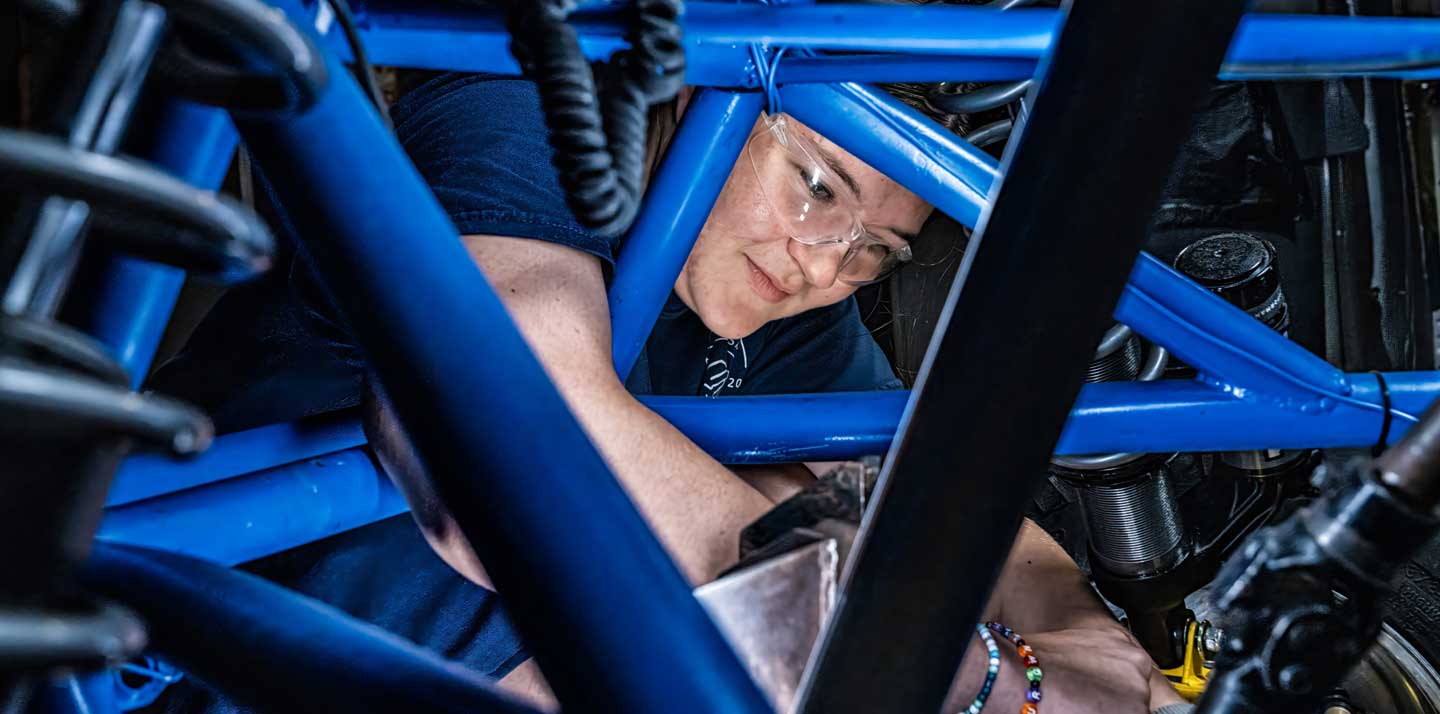 A person wearing safety glasses works on mechanical components.