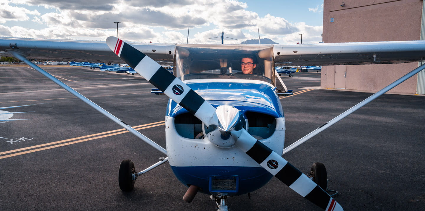 A person sitting in a small airplane on the tarmack of an airport.