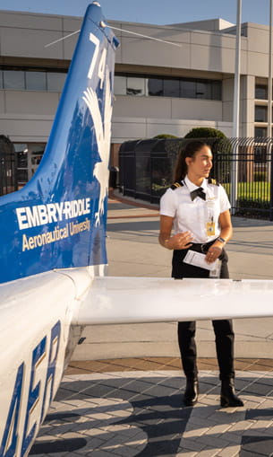 A pilot standing next to a white and blue airplane.