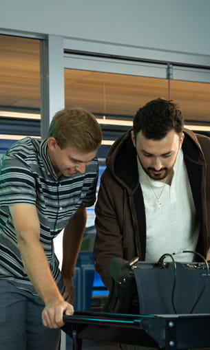 Two people review information together on a laptop in a laboratory setting.