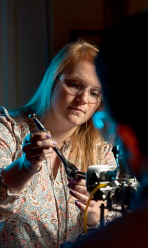 A person wearing protective googles, working on a drone.