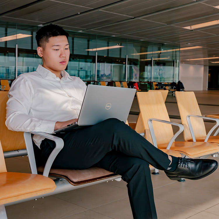 A man sits in an airport terminal with a laptop