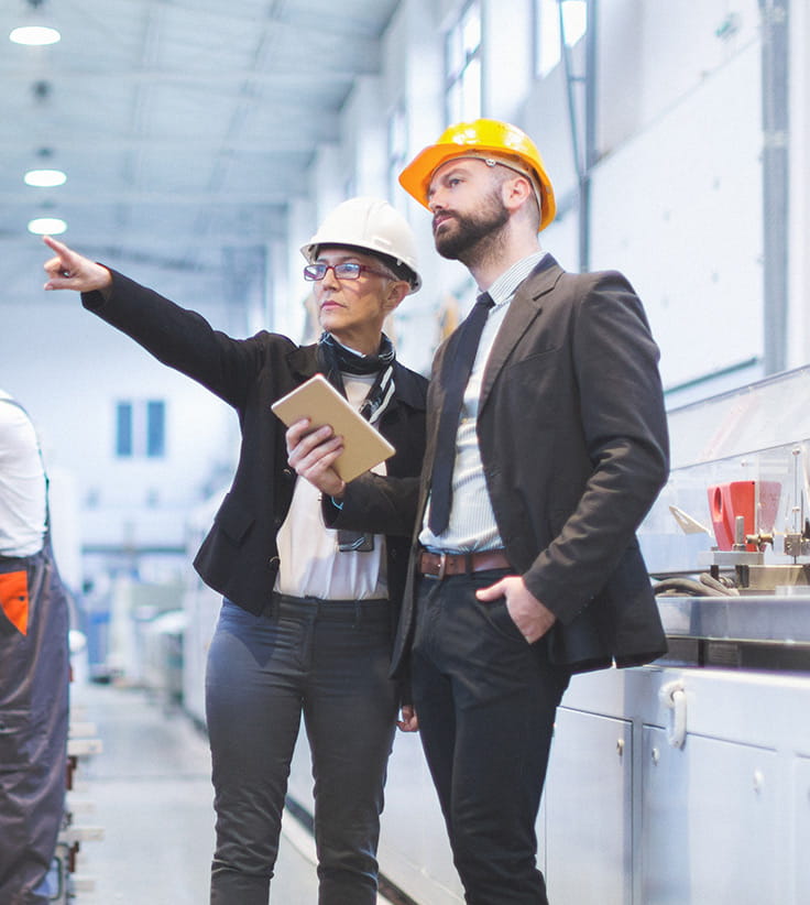 Construction managers discussing plans in a factory setting.