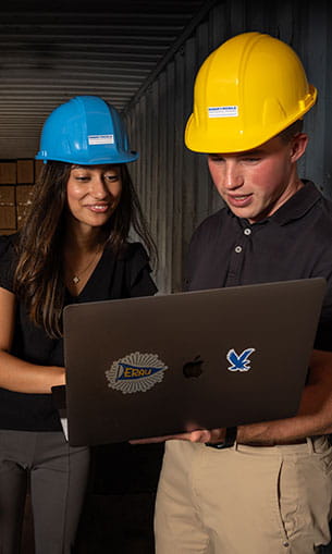Students wearing hard hats looking at a computer