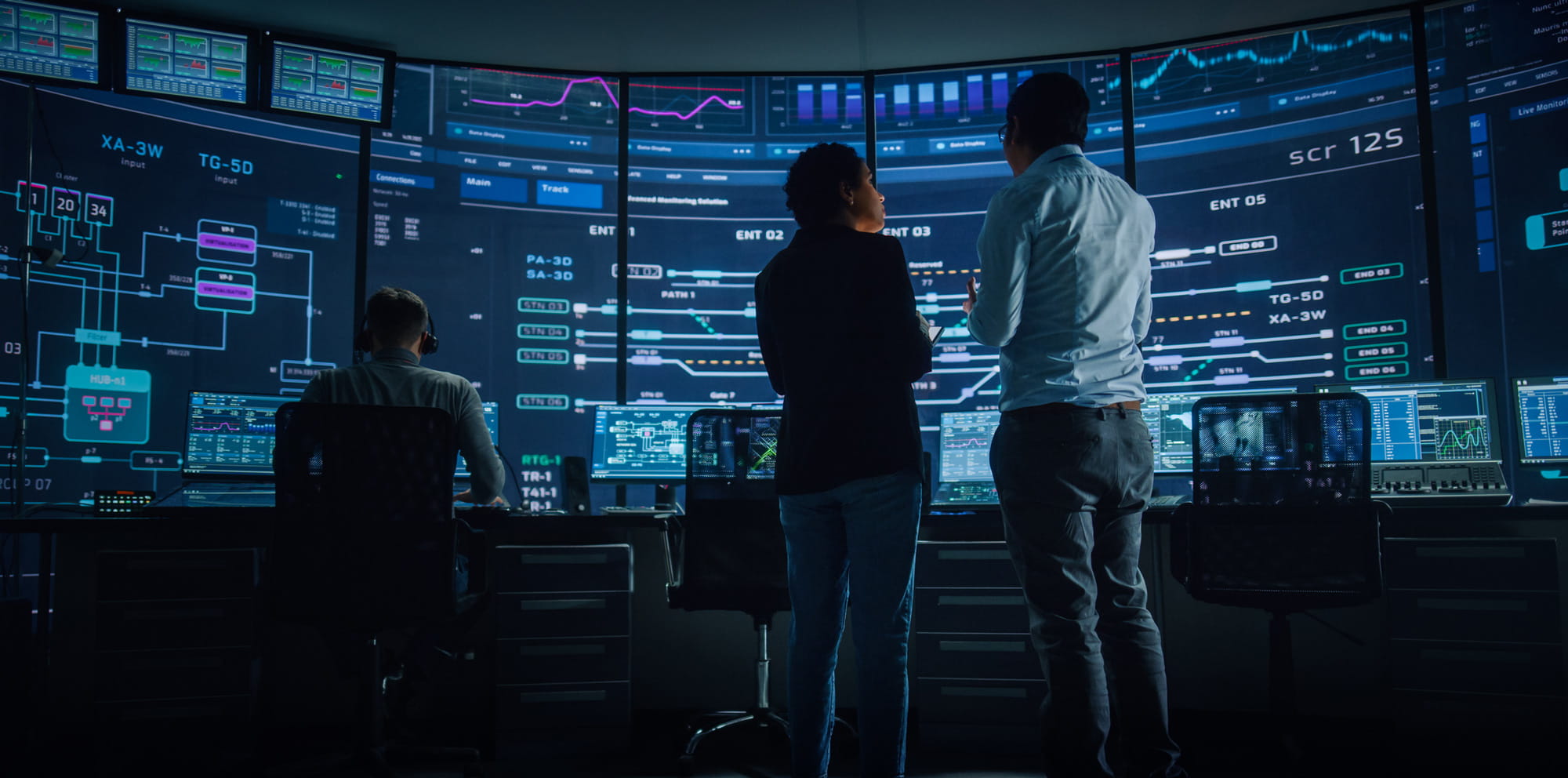People in front of a large screen with charts and graphics.
