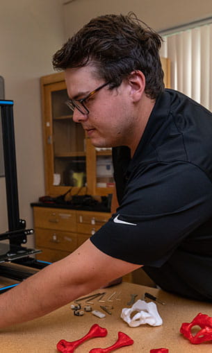Mechanical engineering student Quinn Guzman fabricating femurs and hip models of various densities with a 3D printer