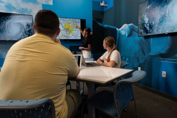 A small group seated in a classroom watching a presentation.
