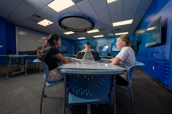 A group of people sitting together at a table in a classroom.