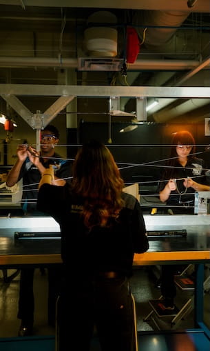 Three students collaborating on a project in a laboratory setting.
