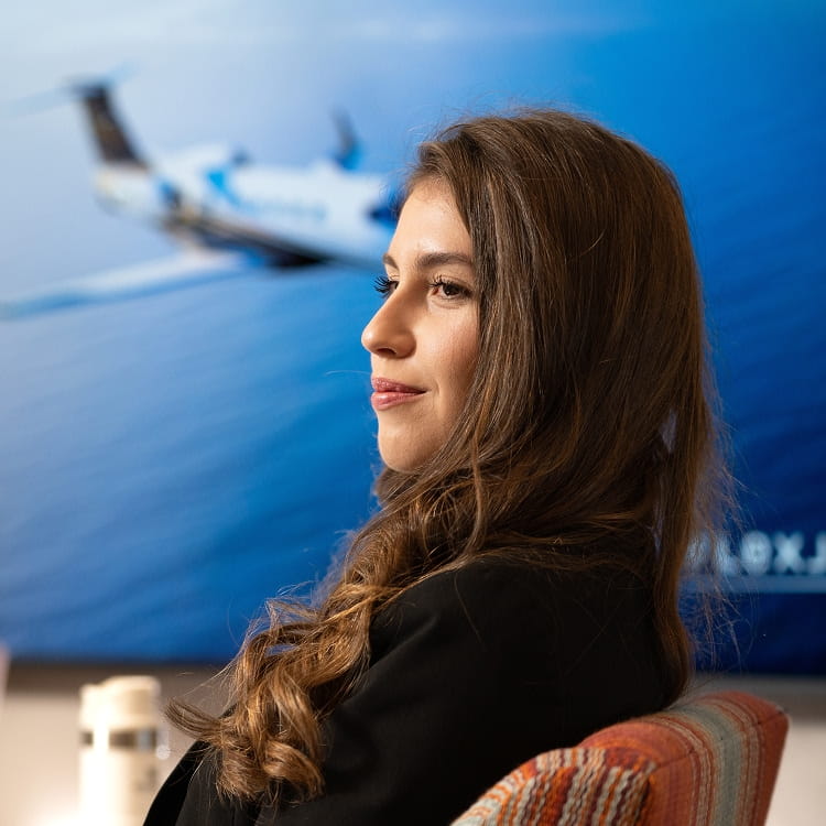 A person sitting in a chair with a poster of an airplane in the background.