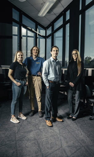 A group of four people standing together in an office.