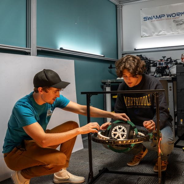 Two students working on computer equipment in a classroom.