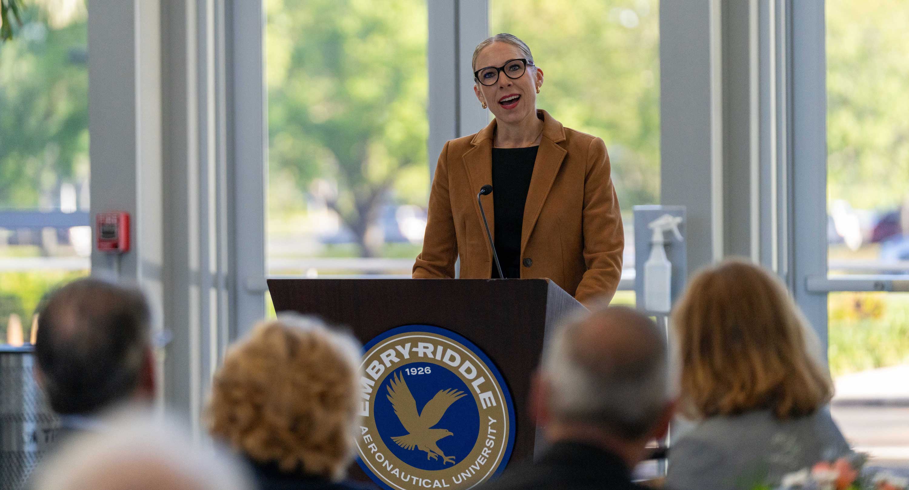 A person stands at a podium delivering a speech to an audience.