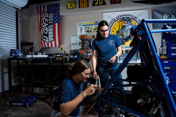 Two individuals working together in a workshop, inspecting equipment.