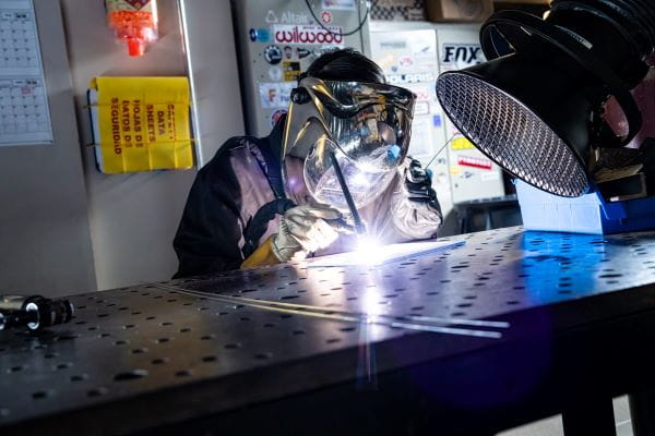 An individual in protective gear welding inside a workshop.