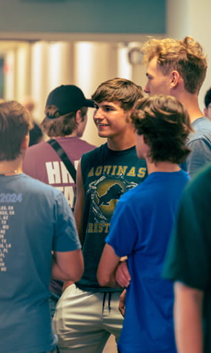 A group of people standing together and talking indoors.